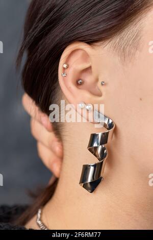 Boucle d'oreille cloutée au cerf sur l'oreille de la femme gros plan. Perçage Banque D'Images