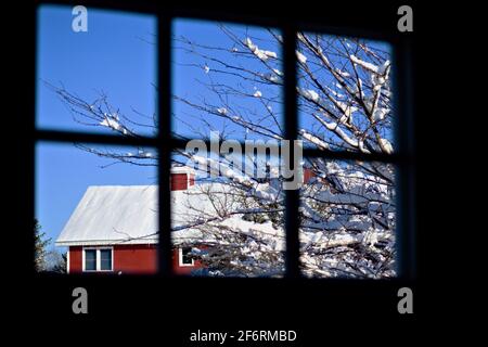 Scène de grange rouge dans la neige vue par une fenêtre Banque D'Images