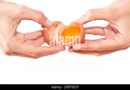 Fabrication de gâteau: Mains ouvrant un oeuf montrant un jaune rouge à l'intérieur avec un fond blanc. Rome, Italie, premier mai 2020 Banque D'Images