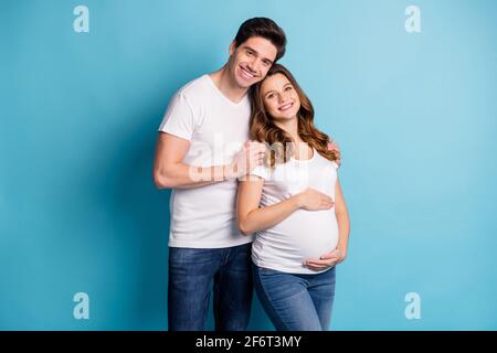 Photo d'une famille charmante et enjouée qui attend bébé en train d'embrasser les bras mains ventre isolé couleur bleu arrière-plan Banque D'Images