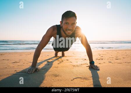 Homme qui fait de la poussée ou de l'exercice sur la plage pendant le coucher du soleil. Un mode de vie sain Banque D'Images