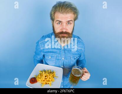 Cuisine de rue. Restauration rapide. Homme avec des pommes de terre frites. Bière. Pommes de terre frites. Homme buvant de la bière et mangeant des pommes de terre frites. Frites et ketchup aux pommes de terre Banque D'Images