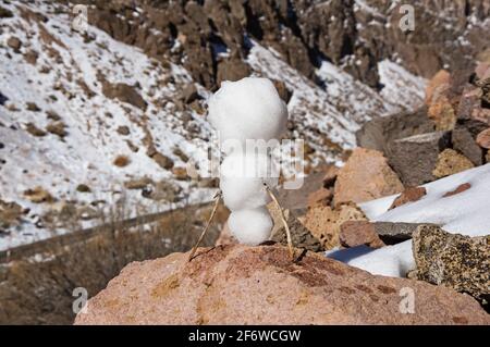 petit bonhomme de neige faisant une tête sur un rocher Banque D'Images
