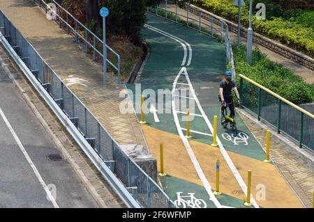 Cycliste sur une piste cyclable le long de la route Tung Chung Waterfront (東涌海濱路) sur l'île Lantau, à Hong Kong Banque D'Images