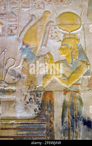 L'Égypte antique peint et sculpté image des dieux Osiris assis avec Isis derrière lui. L'EI porte la couronne cornée de Hathor. Paroi interne à TH Banque D'Images