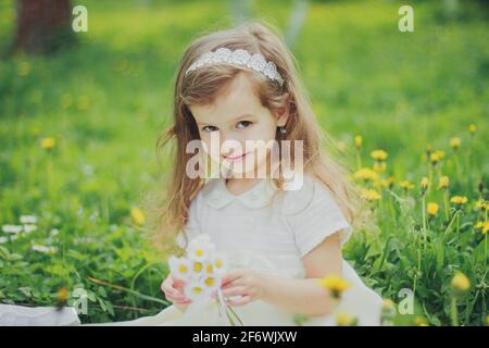 Une fille en robe tient un bouquet de pâquerettes dedans jardin de cerisiers de printemps Banque D'Images