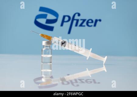 Flacon et seringue de vaccin contre le coronavirus Pfizer avec logo en arrière-plan. LJUBLJANA, SLOVÉNIE : 25 mars 2021 Banque D'Images