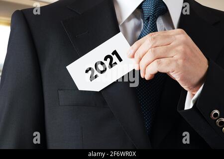 Homme d'affaires prend une carte de visite avec l'année 2021 écrit dessus. Plans d'affaires ou aspirations pour l'année 2021. Banque D'Images