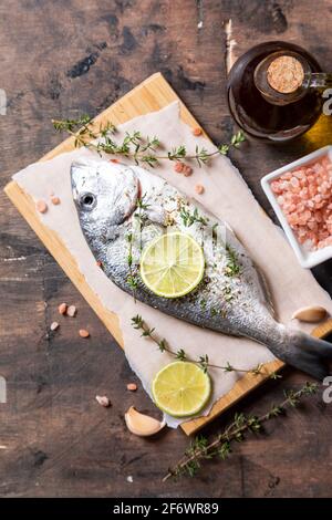 poisson dorado frais cru. poisson dorado et ingrédients de cuisine - lime, sel, huile, ail, thym et herbes Banque D'Images