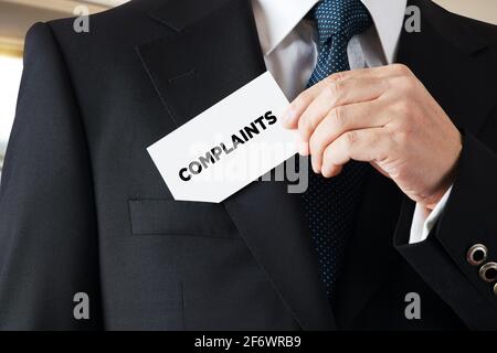 Homme d'affaires prend une carte de visite avec le mot plaintes écrit dessus. Les plaintes des clients et le concept de rétroaction. Banque D'Images