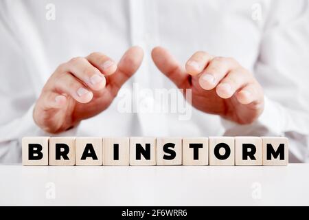 Homme d'affaires tenant ses mains de manière protective sur les cubes de bois avec le mot brainstorming. Brainstorming et création d'idées dans le concept d'entreprise. Banque D'Images