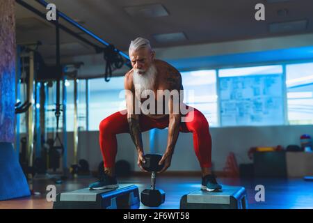 Homme senior faisant des exercices d'entraînement dans la salle de gym - Fit mature Entraînement masculin dans le centre du club de bien-être - corps bâtiment et sport concept de mode de vie sain Banque D'Images