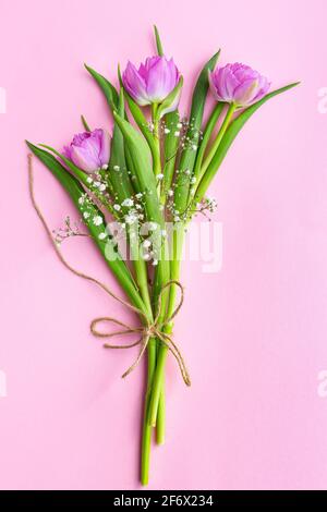 Bouquet de tulipes roses et de gitsophila avec un jute corde sur fond rose Banque D'Images