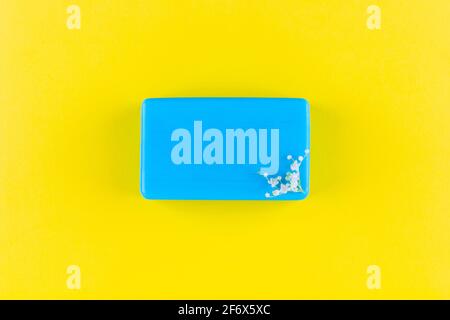 barre de savon bleu fait main avec petites fleurs de sureau blanc sur fond jaune, vue de dessus Banque D'Images