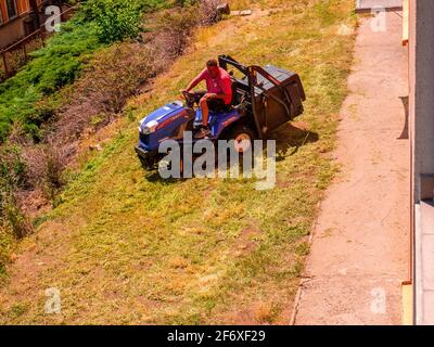 Usti nad Labem / République Tchèque - 06.25.2019: Un homme sur un petit tracteur coupant l'herbe sur une petite bande de pelouse, en face de la maison résidentielle Banque D'Images