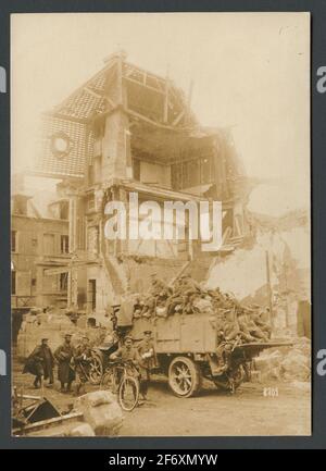 La photo montre des soldats se déplaçant sur une rue en face d'une ruine dans une ville collée.au premier plan, un groupe va à pied.UNE personne conduit un vélo, À côté de lui va un blessé un bras plâtré.derrière ils conduisent un camion transporté à des matériaux de guerre et des soldats assis sur le flocon. La photo montre des soldats se déplaçant dans une rue en face d'une ruine dans une ville brisée.au premier plan, un groupe va à pied.UNE personne conduit un vélo, À côté de lui va un blessé un bras plâtré.derrière ils conduisent un camion transporté à des matériaux de guerre et des soldats assis sur le flocon. Banque D'Images