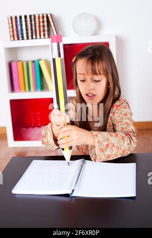 Petite fille à son domicile l'écriture avec un crayon géant Banque D'Images