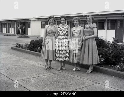 1956, historique, UNE mère avec ses trois filles portant toutes les longues robes de l'époque et prête pour une soirée, debout pour une photo à l'extérieur des chalets de vacances d'un étage dans une station de vacances à Bridlington, une ville balnéaire britannique dans East Yorkshire, Angleterre, Royaume-Uni. Banque D'Images