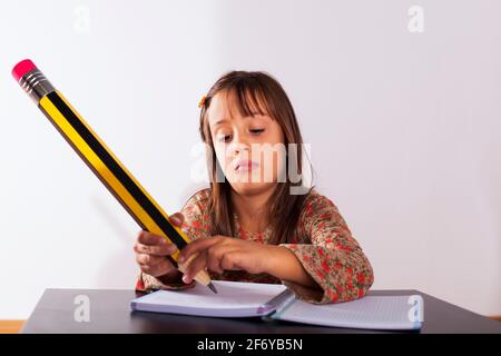 Petite fille à son domicile l'écriture avec un crayon géant Banque D'Images