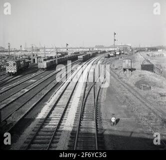 Années 1950, vue historique d'un chemin de fer industriel et du matériel roulant desservant une grande usine de fabrication, Angleterre, Royaume-Uni. Ces chemins de fer privés, avec des liaisons vers le réseau ferroviaire public, étaient autrefois un site commun en Grande-Bretagne, où des trains de marchandises transportent des matières premières lourdes et en vrac le long de voies ferroviaires à distance limitée vers d'autres parties du complexe industriel ou vers un point d'échange avec une ligne ferroviaire principale. La croissance du transport routier et les changements dans la fabrication ont vu le nombre de voies et de voies ferrées industrielles diminuer rapidement. Banque D'Images