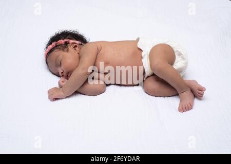 Nouveau-né bébé fille de 3 semaines, dormir sur le côté, pleine longueur Banque D'Images