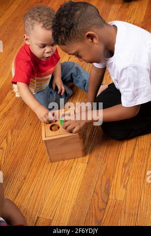 Frères de 2 et 6 ans jouant avec un trieur de forme géométrique Banque D'Images