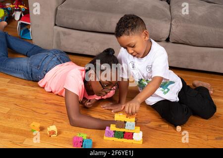Fille, 11 ans, jeu avec blocs avec son frère de 6 ans Banque D'Images
