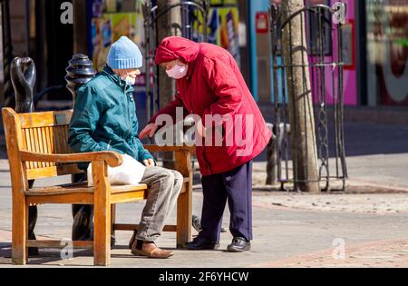 Dundee, Tayside, Écosse, Royaume-Uni. 3 avril 2021. Météo au Royaume-Uni : soleil printanier avec une brise fraîche à travers le nord-est de l'Écosse avec des températures atteignant 12°C. Les gens continuent de passer du temps en plein air à socialiser dans la ville de Dundee avec de nombreux magasins de haute rue encore fermés dans la région de Tayside pendant le niveau 4 Covid-19 Lockdown. Un couple âgé est bien conscient des directives de distanciation sociale et du port de masques de visage passer du temps ensemble dehors en profitant du temps ensoleillé dans le centre-ville. Crédit : Dundee Photographics/Alamy Live News Banque D'Images