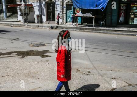 Gaza, la bande de Gaza, Palestine. 3 avril 2021. Une fillette palestinienne portant un masque facial protecteur descend une rue dans le nord de la bande de Gaza.le Ministère de l'intérieur de la ville de Gaza a annoncé le 01 avril 2021 le verrouillage complet le vendredi et le samedi jusqu'à nouvel ordre de freiner la propagation de la COVID-19. Credit: Mahmoud Issa/Quds Net News/ZUMA Wire/Alay Live News Banque D'Images