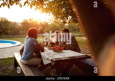 groupe d'amis en train de rencontrer au coucher du soleil près de la piscine extérieur dans la nature Banque D'Images