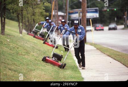 Austin Texas USA, septembre 12 1988 : les employés d'une entreprise d'aménagement paysager tond une pelouse à flanc de colline. ©Bob Daemmrich Banque D'Images