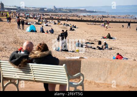 Portobello, Écosse, Royaume-Uni. 3 avril 2021. Le week-end de Pâques, la foule descend sur la plage et la promenade de Portobello pour profiter au maximum des restrictions de voyage récemment relaxantes de Covid-19 et du soleil chaud avec un ciel bleu ininterrompu. Pic ; la plage est occupée par de petits groupes de personnes. Iain Masterton/Alay Live News Banque D'Images