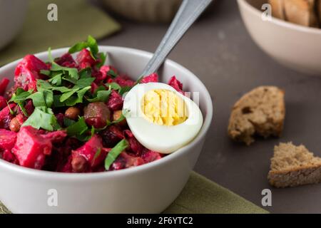 Vinaigrette russe à salade dans des assiettes avec œufs durs et pain noir, salade de légumes durs et marinés et pois verts en conserve Banque D'Images