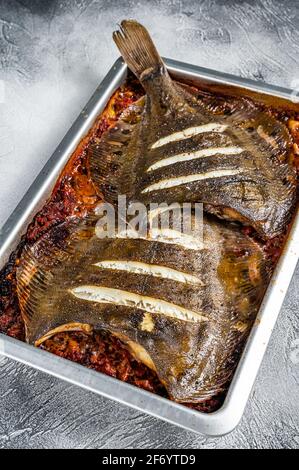 Poisson plat grillé dans une sauce tomate sur une plaque de cuisson fond blanc. Vue de dessus Banque D'Images