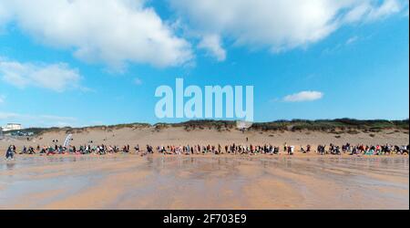 Newquay, Cornwall, Angleterre, 3 avril 2021. Météo au Royaume-Uni : rafraîchissez-vous avec le soleil pour un cours de yoga de masse impliquant plus de 300 participants. Yoga disco silencieux organisé par Anthony Durkin DJ en combinaison avec le yoga Oceanflow. Plage de Fistral. Crédit : Robert Taylor/Alay Live News Banque D'Images