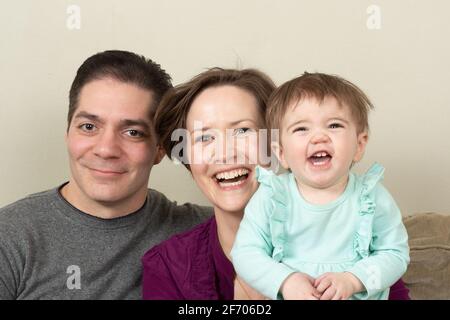 bébé fille de 10 mois riant heureux gros plan portrait de famille avec ses parents Banque D'Images