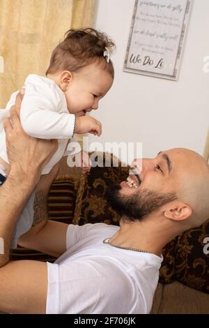 bébé fille de 7 mois, interagissant avec le père, tenue élevé Banque D'Images