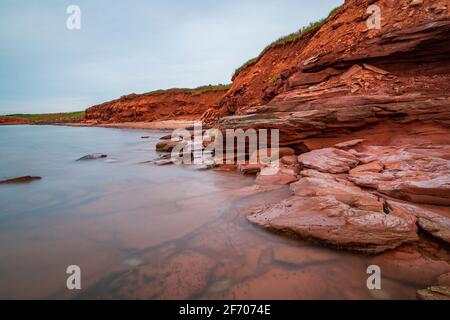 À la plage de Cavendish, sur l'Île-du-Prince-Édouard du Canada, le grès rouge plat a été surmonté par les vents et les courants océaniques. La falaise rouge surplombe t Banque D'Images