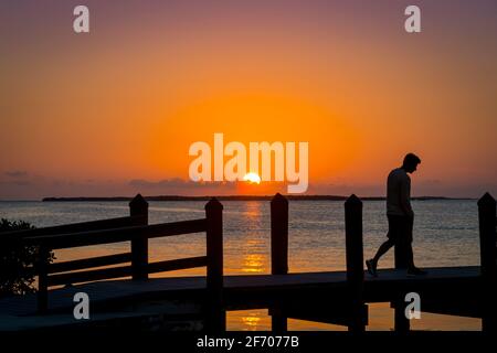 Triste homme marchant sur la jetée au coucher du soleil, Key Largo Florida USA Banque D'Images