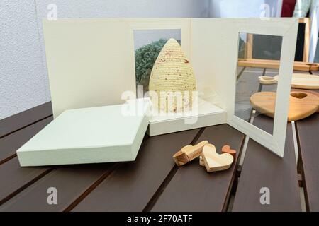 Œuf de Pâques au chocolat blanc avec peinture comestible de couleur cuivre. Sur une boîte blanche ouverte. À côté de coeurs en bois. Banque D'Images