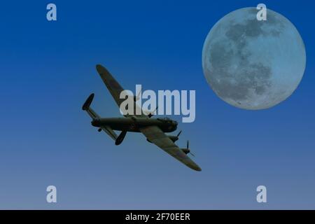 Un bombardier lourd de l'époque de la Seconde Guerre mondiale d'Avro Lancaster à la lumière d'une pleine lune Banque D'Images