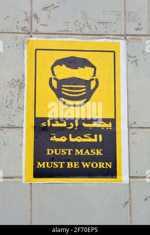 L'autocollant mural en arabe et en anglais indique que les masques doivent être portés, la traduction des mots arabes (masque facial est un must) Banque D'Images