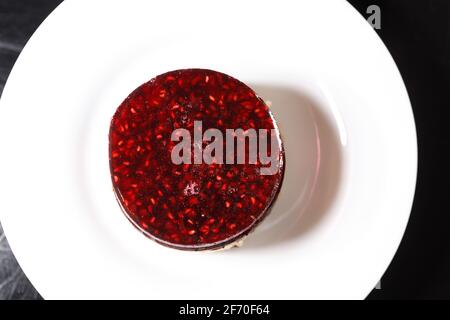 Pongez le gâteau sur une assiette recouverte de gelée de framboise. Dessert sucré. Banque D'Images