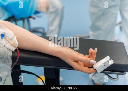 La main du patient se trouve sous l'IV avec un oxymètre de pouls sur le doigt. Services médicaux. Banque D'Images