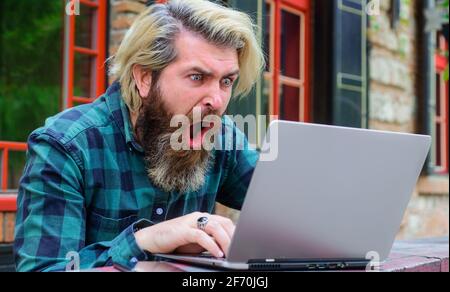 Jeux en ligne. Gagner en ligne. Travail en ligne. Homme barbu plein d'enthousiasme avec un ordinateur portable à l'extérieur. Freelance Banque D'Images