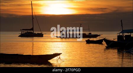 Des bateaux amarrés dans la baie au large du village de Logon, île de Malapascua. Mer de Visayan, Cebu, Philippines. Silhoueted formes de bateaux au crépuscule. Banque D'Images