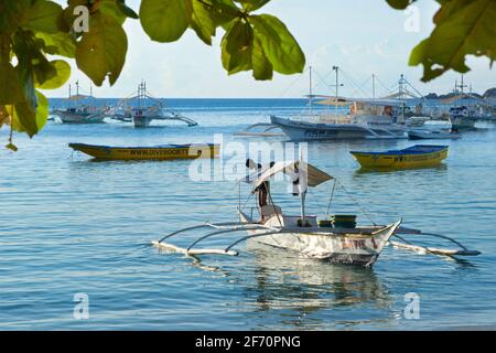 Logon village, île Malapascua, avec un pêcheur qui s'occupe de son canot d'outrigger. Mer de Visayan, Cebu, Philippines. Banque D'Images