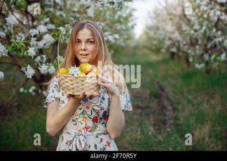 Une jeune femme en robe blanche se tient dans le milieu du verger de pomme en fleur Banque D'Images