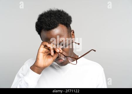 Épuisé Black man enlever des lunettes se frottant les yeux se sent fatigué après le travail sur ordinateur portable. Travail excessif. Banque D'Images