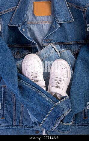 veste en denim bleu, baskets en cuir blanc, sur fond blanc. Nettoyer les vêtements de marque. Créez un modèle pour votre style. Banque D'Images